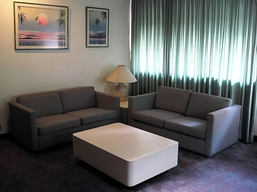 Ett hotellrum med två soffor, ett soffbord, en lampa och två inramade tavlor på väggen.
