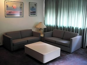 A hotel room with two sofas, a coffee table, a lamp, and two framed pictures on the wall. - Cuarta Avenida Suites (Caracas)