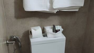 Un baño con inodoro, ducha y cubo de basura.