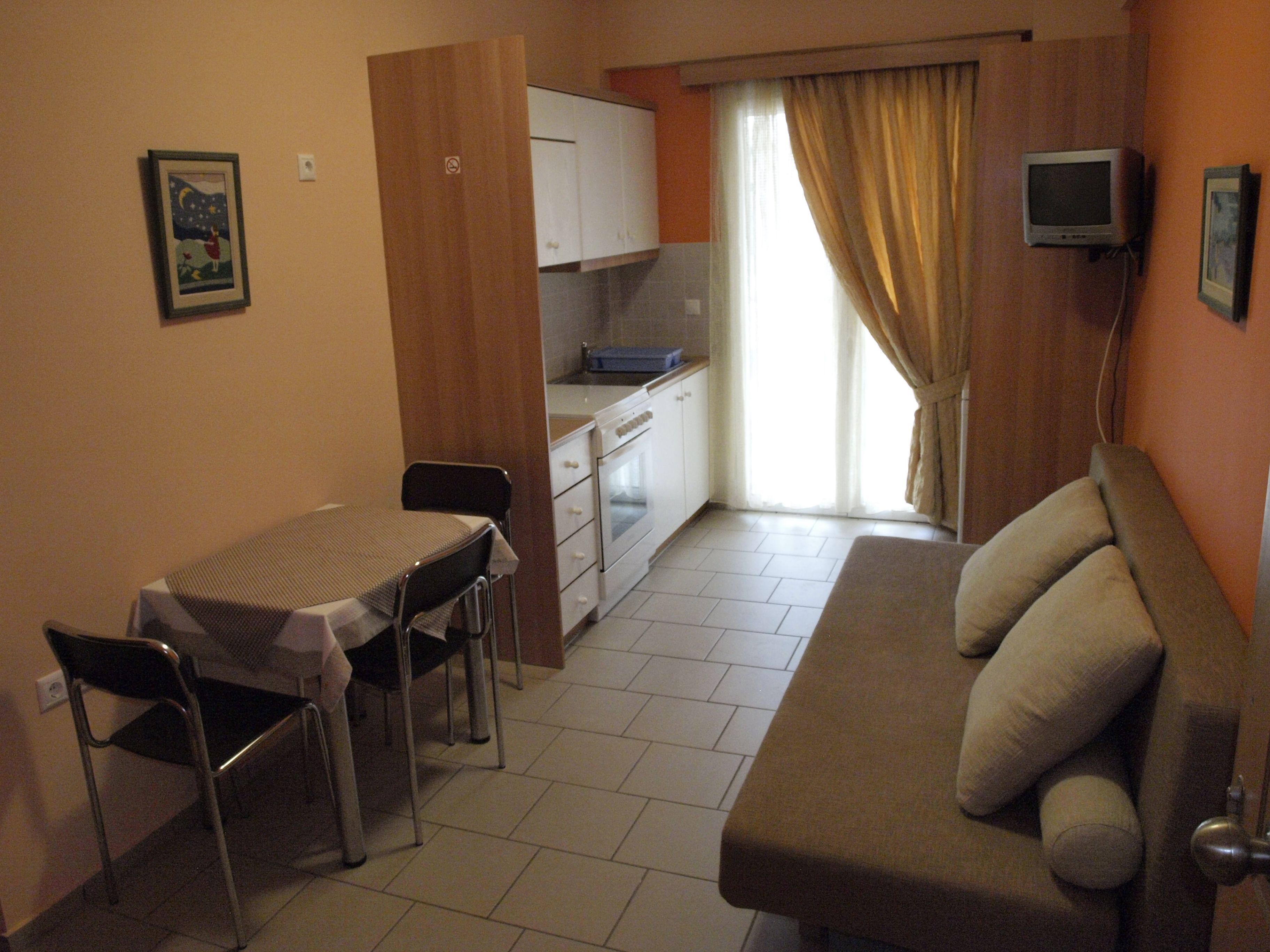 A compact living space with a kitchenette, a dining area with a table and chairs, and a sofa.
