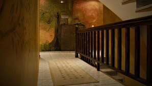 A reception area with a wooden staircase, a reception desk, and a wall mural. - Xenonas Drimos (Karpenisi)