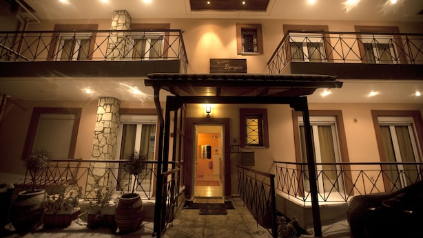 A multi-level building with a stone facade, balconies, and a covered entrance. - Xenonas Drimos (Karpenisi)