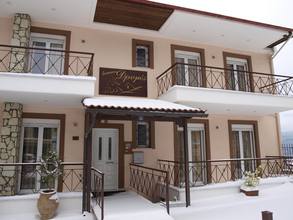 A two-story building with a balcony, a signboard, and a door. - Xenonas Drimos (Karpenisi)