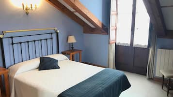 A bedroom with a bed, a nightstand, a lamp, and a window with curtains.