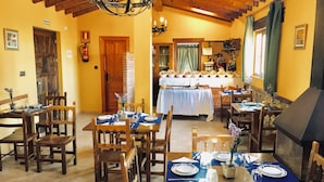 A dining area with wooden tables and chairs, a chandelier, and a buffet setup.