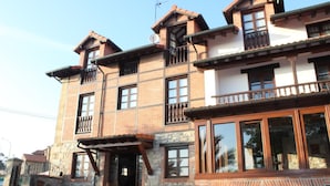 A multi-story building with a stone facade, multiple balconies, and large windows.