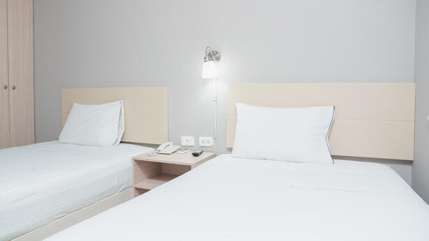 Ett hotellrum med två sängar, ett nattduksbord med en telefon, en lampa och en garderob.