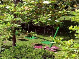 Un jardín con un columpio, césped y flores rosadas.