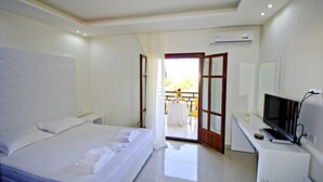 Hotelkamer met een bed, een bureau met een computer, een airconditioner en uitzicht op het buiten.