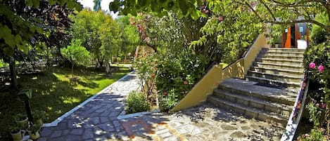 Una escalera de piedra que conduce a un edificio, rodeado de follaje y plantas en macetas.