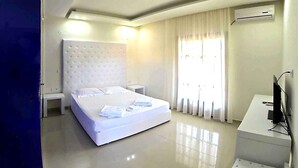 Een moderne hotelkamer met een groot bed, een nachtkastje, een televisie en een airconditioner.
