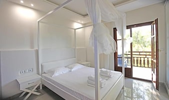 Un dormitorio con cama con dosel, una mesita de noche y vistas al exterior a través de una puerta.