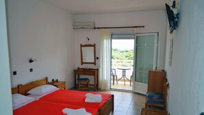 A hotel room with two beds, a desk, a chair, and a balcony with a view. - Achillion (Thasos)