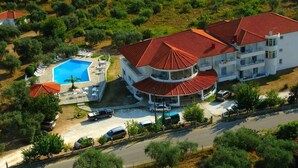 A large building with a swimming pool, surrounded by greenery and a curved roof. - Achillion (Thasos)