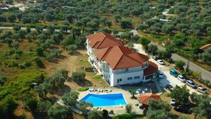 A large building with a swimming pool, surrounded by olive trees and a road. - Achillion (Thasos)