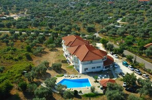 A large building with a swimming pool, surrounded by olive trees and a road. - Achillion (Thasos)