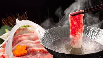 A hot pot with raw meat being cooked.