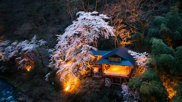 A traditional Japanese house surrounded by trees with illuminated windows.