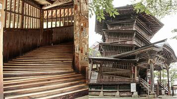 Una escalera de madera japonesa tradicional que conduce a una pagoda de varios niveles con techo de paja.