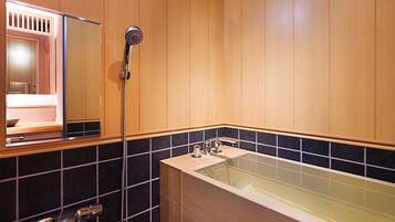 A bathroom with wooden paneling, a bathtub, a shower, and a mirror.