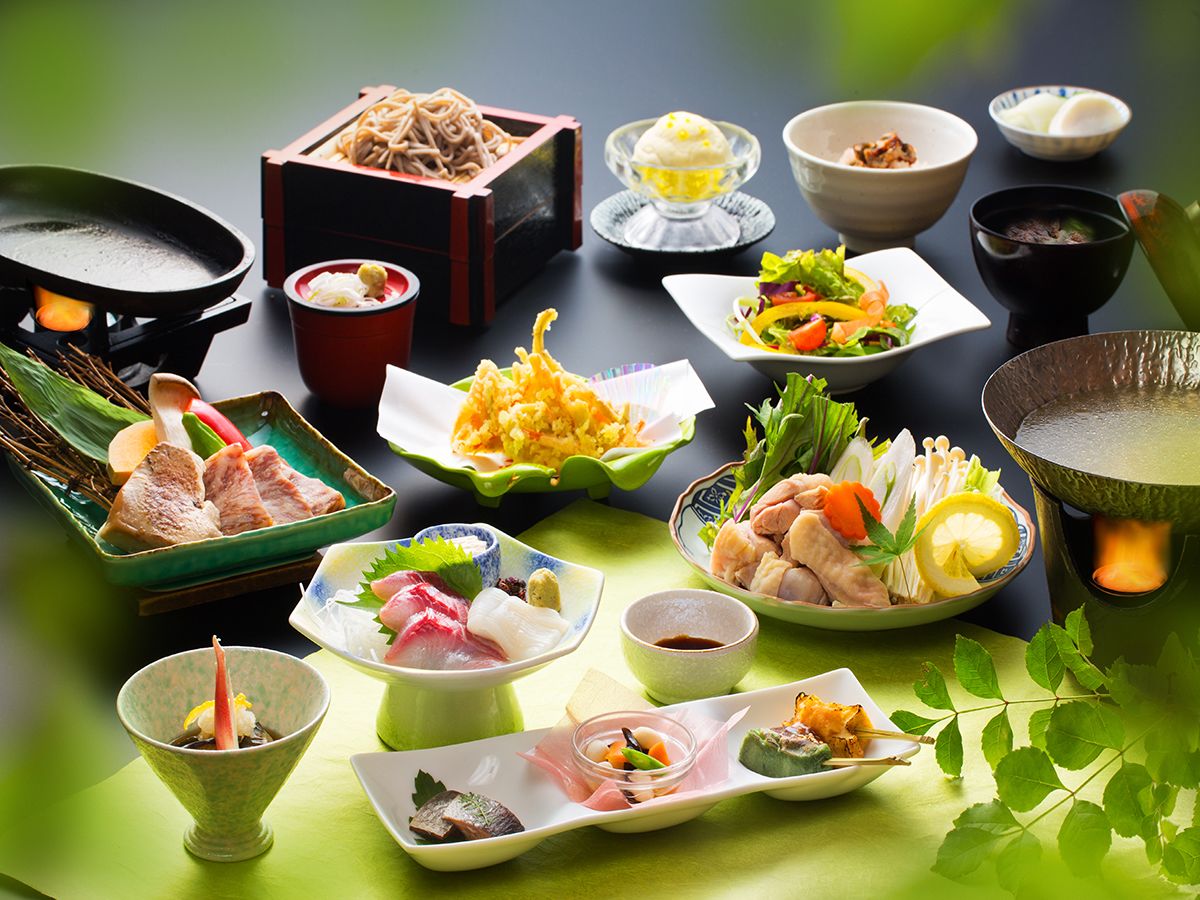 A variety of Japanese dishes arranged on a table with a green tablecloth.
