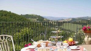A table set for a meal with a view of rolling hills in the background. - Colleverde Country House Beauty&Wellness (Urbino)