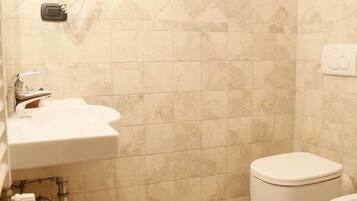 A bathroom with a sink, toilet, and bidet.