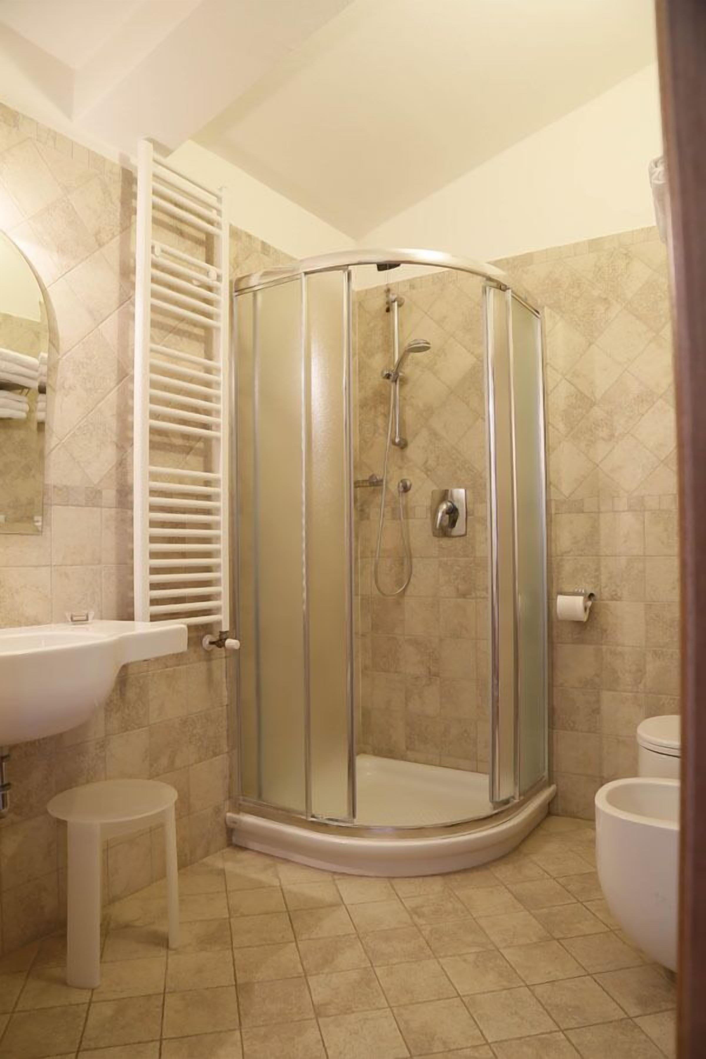 A bathroom with a glass-enclosed shower, a white sink, and a toilet.