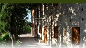 A building with a stone facade, wooden doors, and a pathway leading to the entrance. - Colleverde Country House Beauty&Wellness (Urbino)