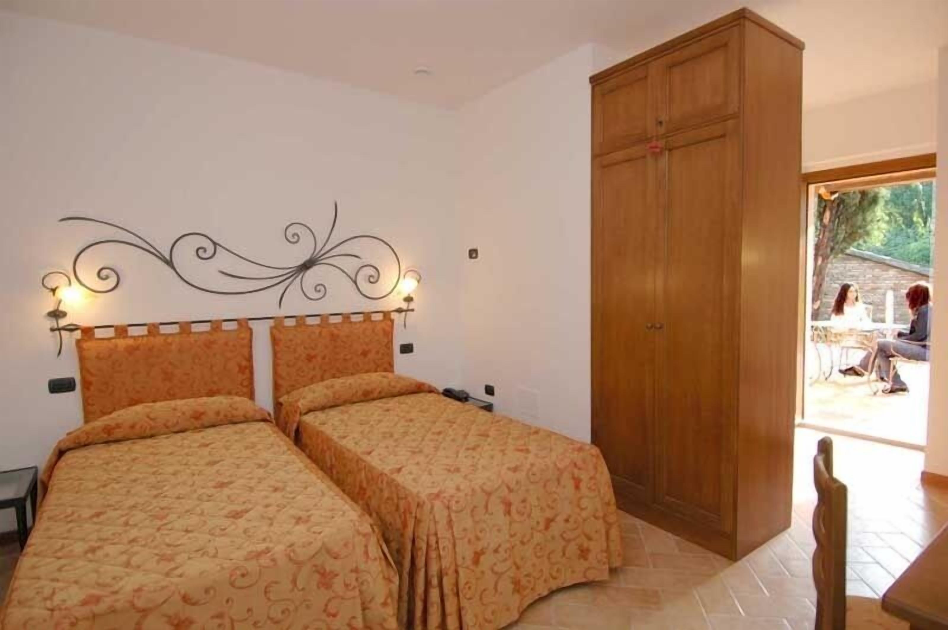 Ein Schlafzimmer mit zwei Betten, einem Holzschrank und einem dekorativen Wandpaneel als Kopfteil.