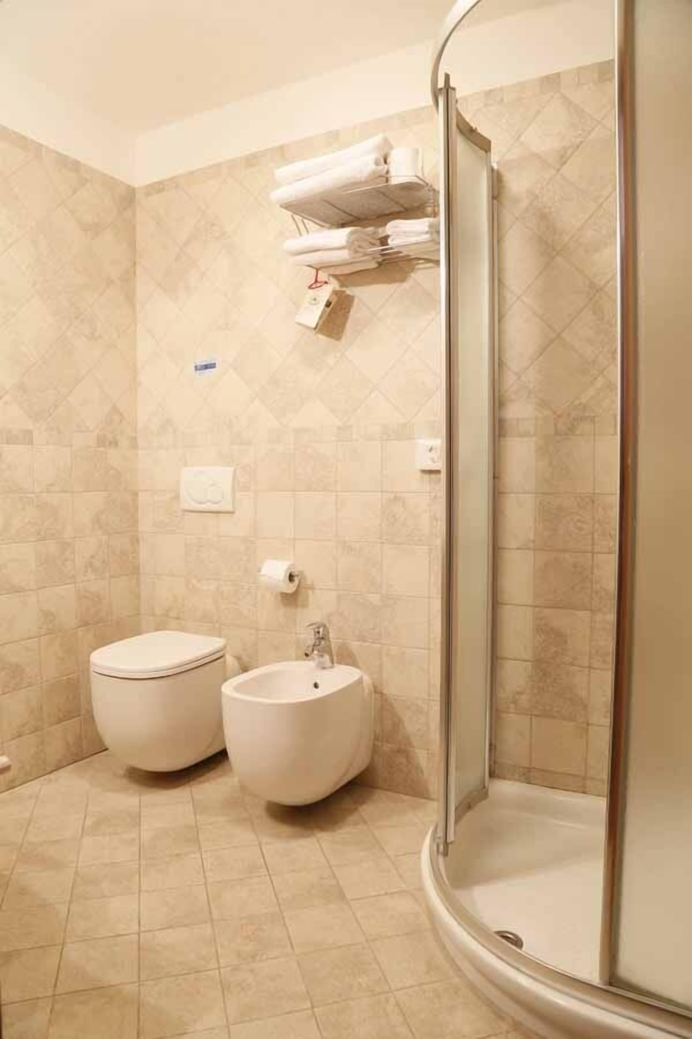 Un baño con dos lavamanos, un inodoro y una ducha con mampara de vidrio.
