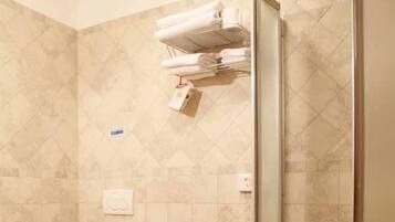 Un baño con dos lavamanos, un inodoro y una ducha con mampara de vidrio.
