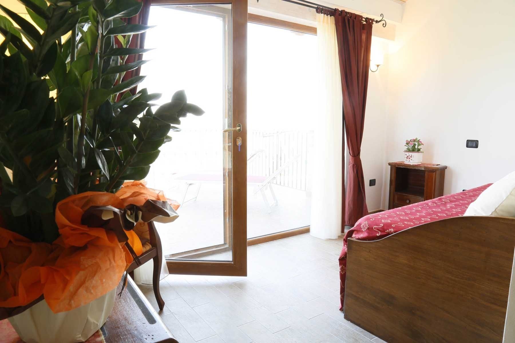 Ein Schlafzimmer mit einem hölzernen Bett, einem kleinen Nachttisch, einer Topfpflanze und einer Glastür, die zu einem Außenbereich führt.