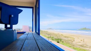 A wooden deck with a view of a beach and ocean. - Praia Hotel Imbituba (Imbituba)