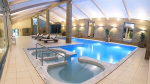 A large indoor swimming pool with a jacuzzi, lounge chairs, and a sun terrace. - Praia Hotel Imbituba (Imbituba)