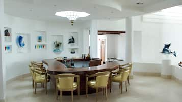 Un comedor amplio con una mesa redonda rodeada de sillas, una zona de cocina con barra y vistas al exterior.