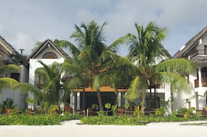 A resort with thatched-roof buildings, palm trees, and a sandy beach. - Village du Pecheur (Praslin Island)
