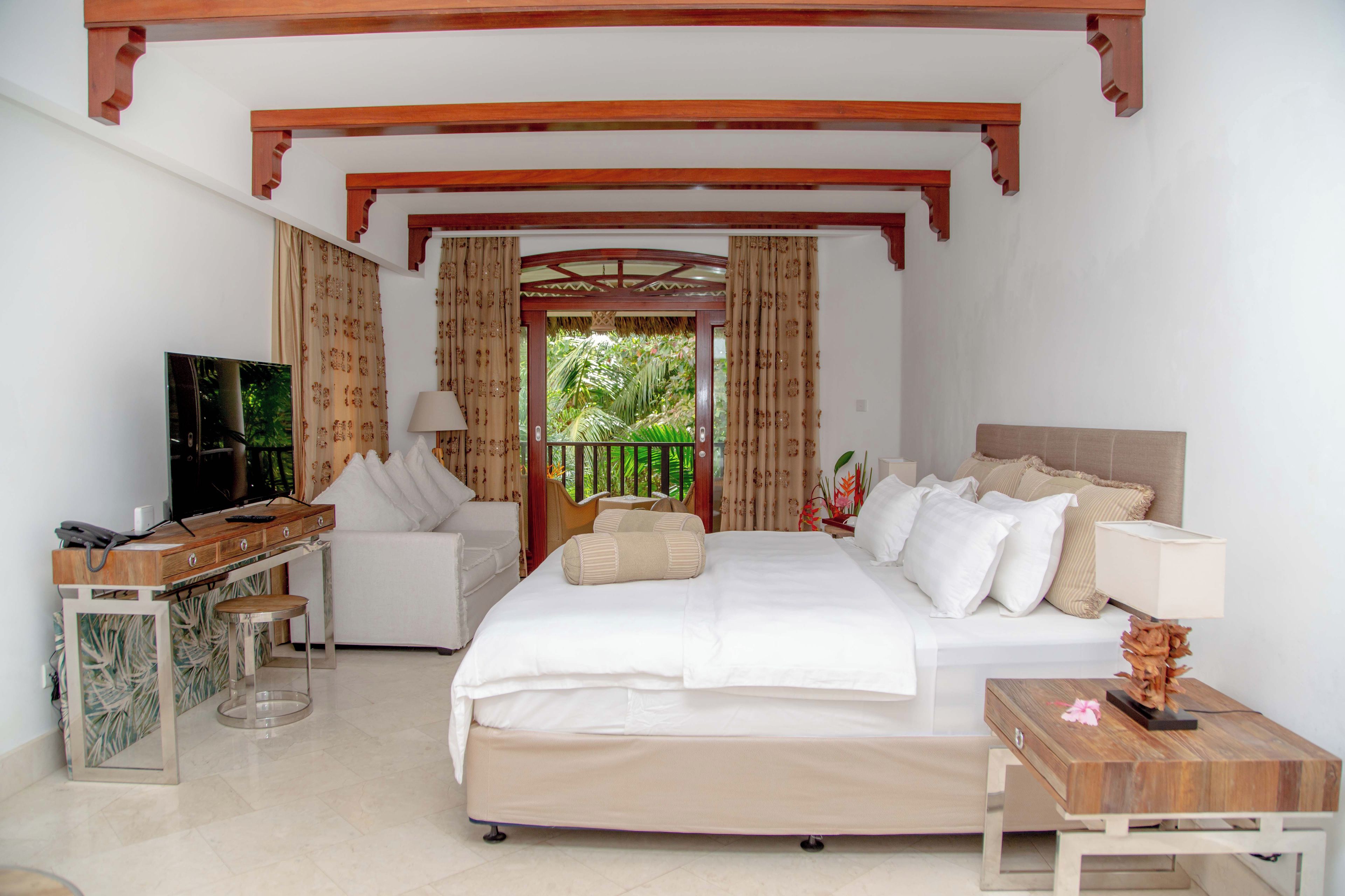 Una habitación de hotel con una cama, un escritorio, un televisor y una ventana con cortinas.
