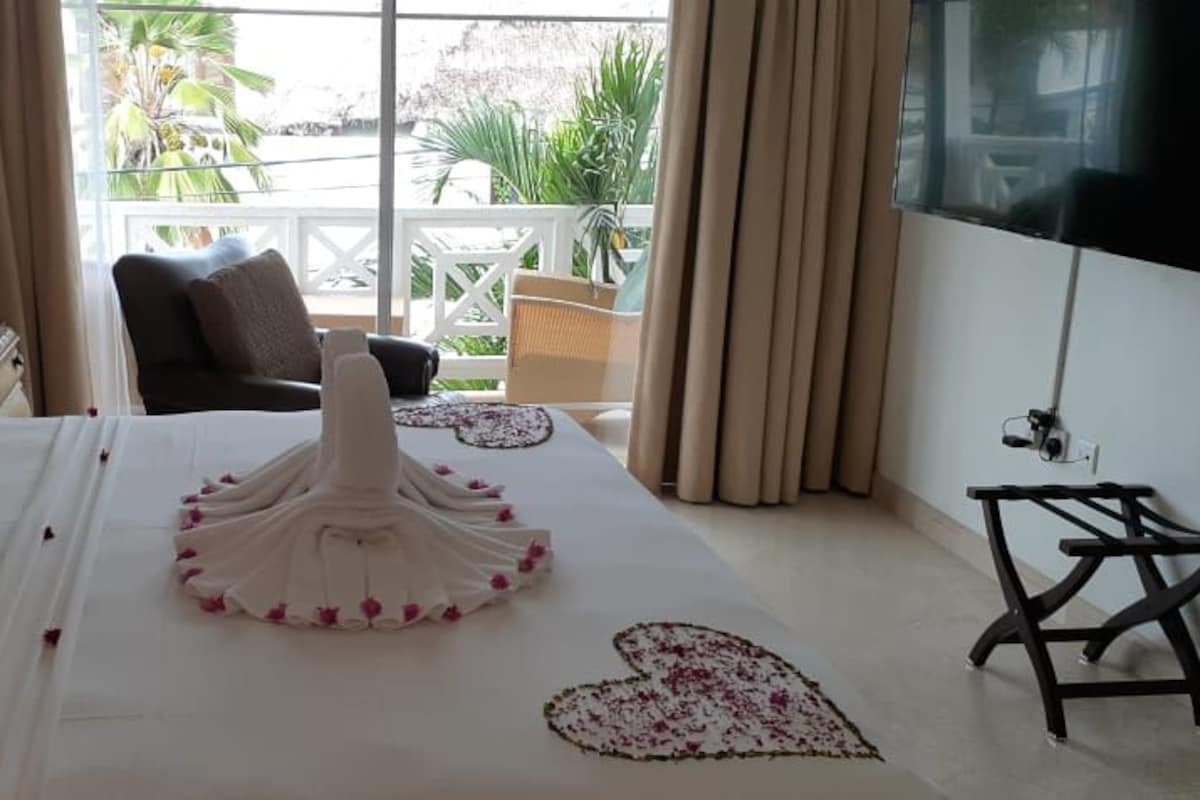 A hotel room with a bed, a TV, a chair, and a view of the outdoors.