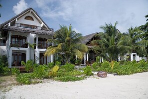 A beachfront hotel with a two-story structure, a thatched roof, and a dining area with outdoor seating. - Village du Pecheur (Praslin Island)