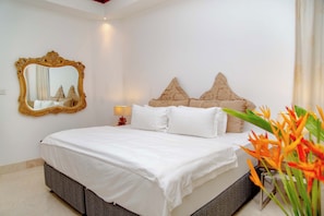 Una habitación de hotel con una cama grande, un espejo y una mesita de noche con lámpara.