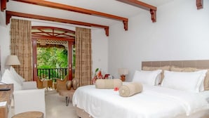 A bedroom with a bed, a desk, and a chair. There is a balcony with curtains. - Village du Pecheur (Praslin Island)