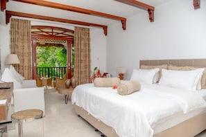 Une chambre avec un lit, un bureau et une chaise. Il y a un balcon avec des rideaux.