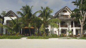 A beachfront hotel with multiple buildings, palm trees, and a sandy beach. - Village du Pecheur (Praslin Island)