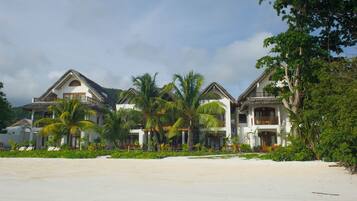A beachfront property with multiple villas, each featuring a balcony and surrounded by lush greenery.