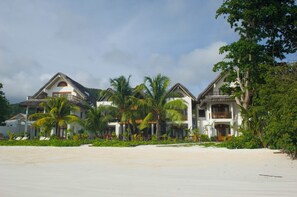 A beachfront property with multiple villas, each featuring a balcony and surrounded by lush greenery. - Village du Pecheur (Praslin Island)