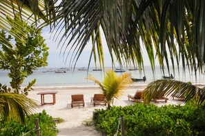 A beach with lounge chairs and a palm tree. - Village du Pecheur (Praslin Island)
