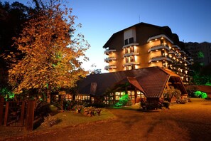Een meerhoog hotel met een modern design, met balkons en een goed verlichte entree.