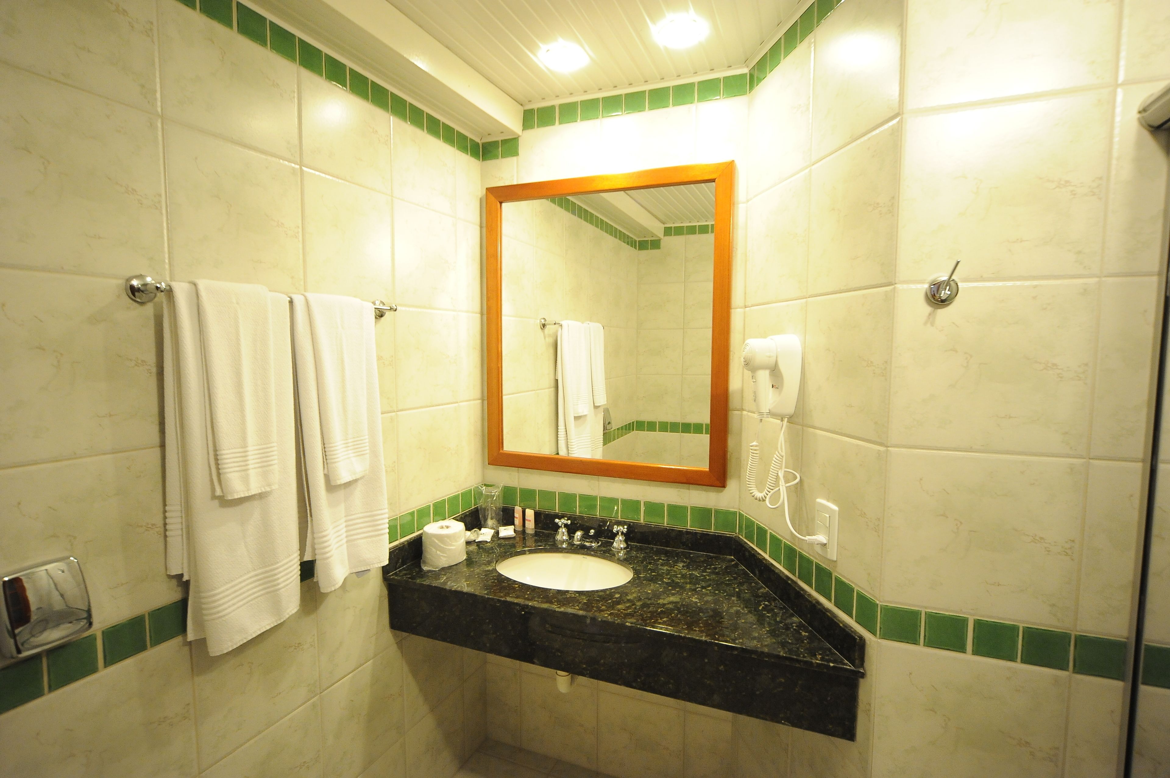 Baño con lavamanos, espejo y toallero.