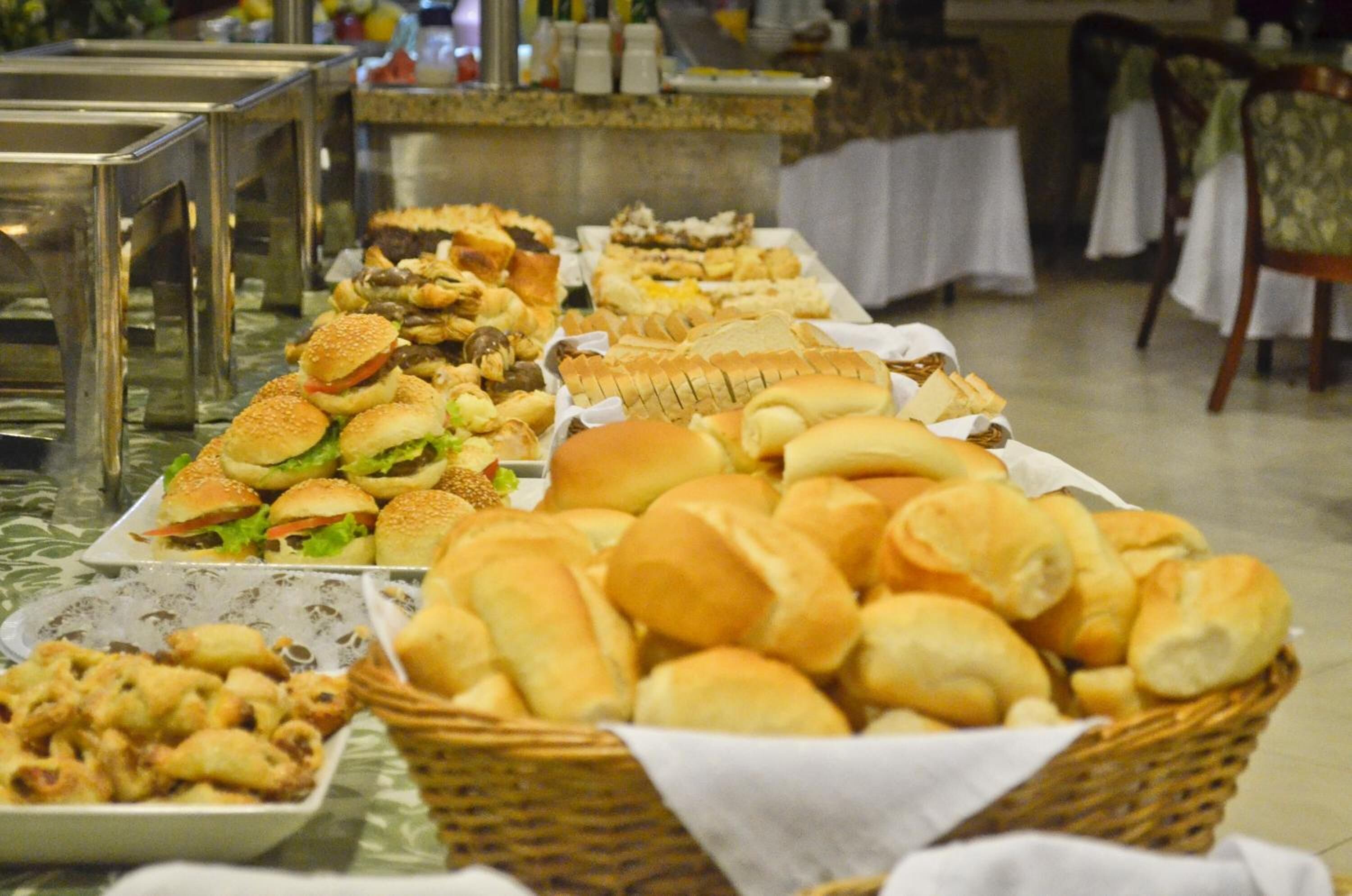 A buffet with various food items including sandwiches, rolls, and pastries.